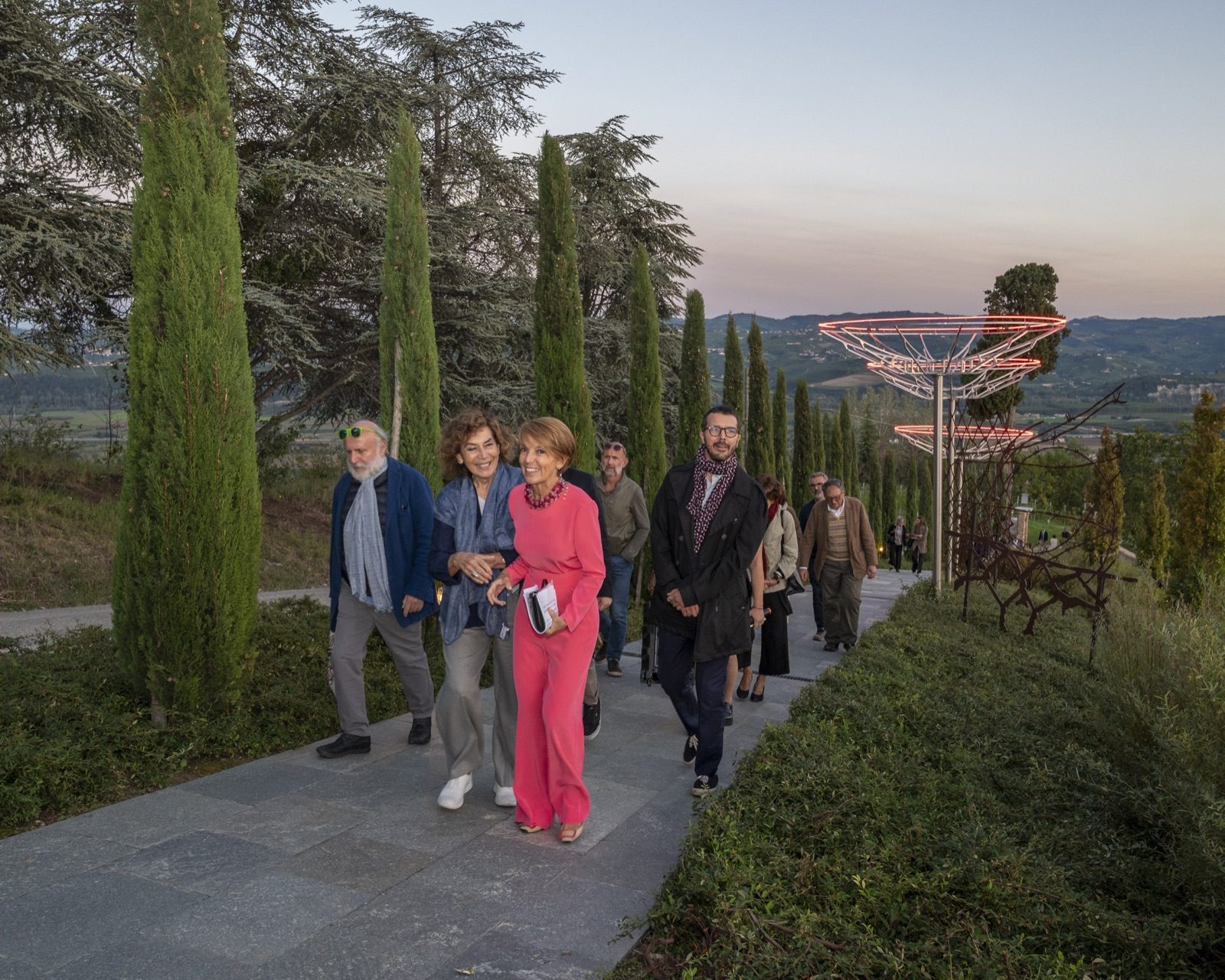 Visitatori tra i cipressi verso un'installazione